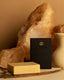 UMM Skincare soap bar resting on countertop surrounded with crystals and a clay vase.