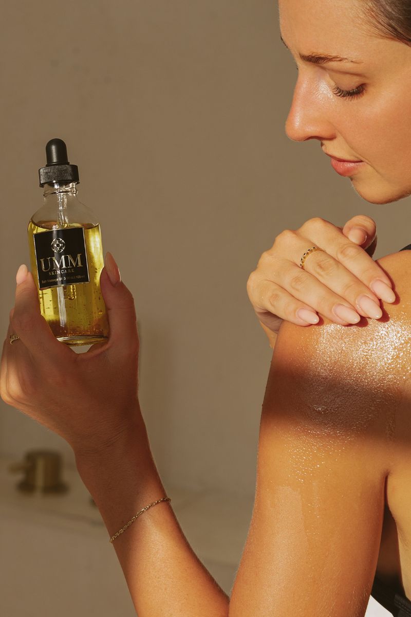 Woman applying the pre-shower body massage oil to her shoulders as a luxurious pre bathing ritual.
