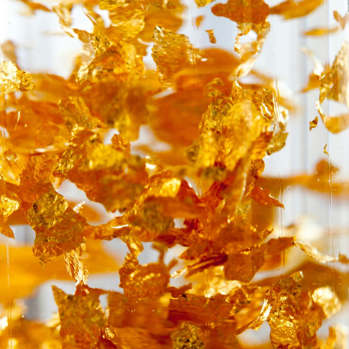 Floating gold flakes in oil, used in healing Ayurvedic skincare rituals for their antioxidant and skin healing properties.