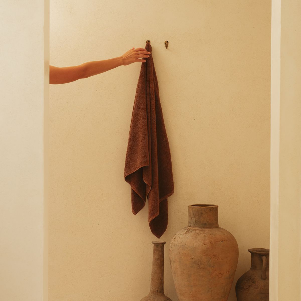 Woman's hand reaching for bath towel as she gets out of the shower.