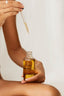 Woman applying pre-shower oil to her legs, as she experiences UMM Skincare's elevated bathing rituals.