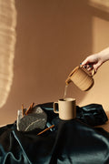 Pouring water warm water from a clay pot into a cup to brew herbal tea.