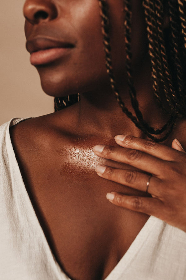 Woman applying skin polishing body scrub to her chest as part of an opulent body care treatment. 